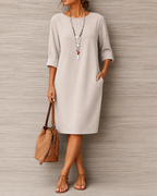 Women's midi dress in off white with a flowing skirt, styled for casual and smart-casual outfits.