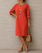 Women's midi dress in orange red with a flowing skirt, styled for casual and smart-casual outfits.