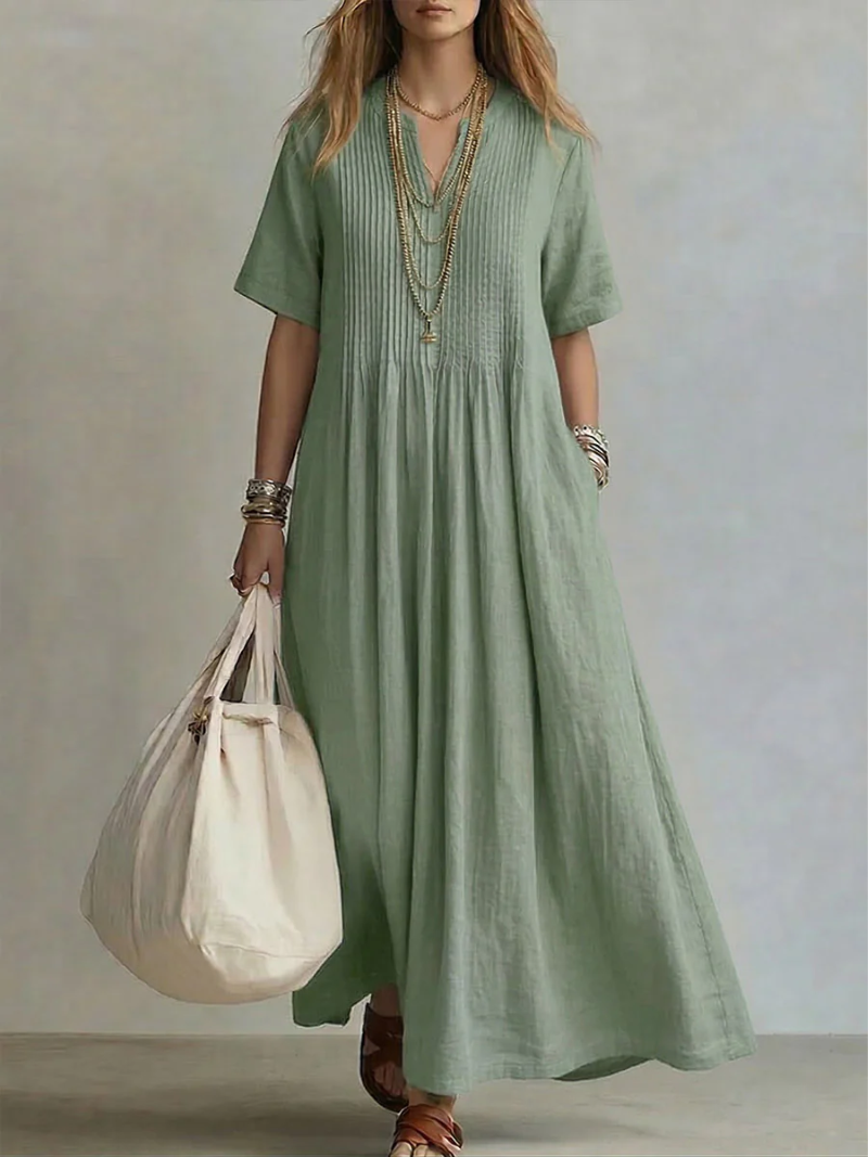 Women's pleated dress in green with a flowing pleated skirt, styled for casual and smart-casual outfits.