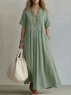 Women's pleated dress in green with a flowing pleated skirt, styled for casual and smart-casual outfits.