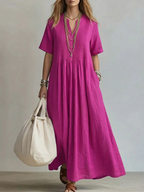 Women's pleated dress in pink with a flowing pleated skirt, styled for casual and smart-casual outfits.