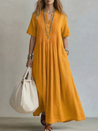 Women's pleated dress in yellow with a flowing pleated skirt, styled for casual and smart-casual outfits.