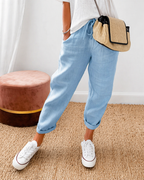 Women's relaxed fit trousers in light blue with elasticated waist, styled for casual and smart-casual outfits.