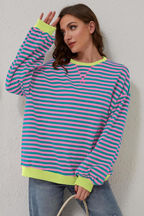 Women's sweatshirt in pink and blue with striped pattern, styled for casual and smart-casual outfits.