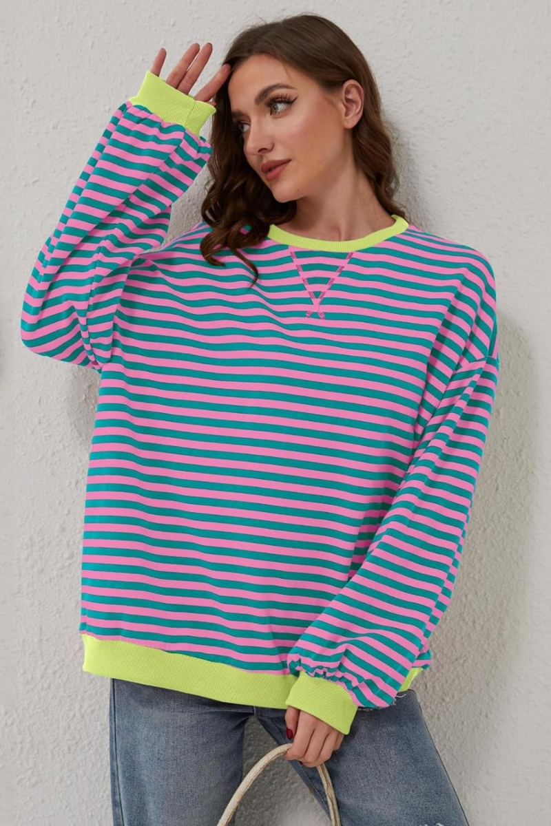 Women's sweatshirt in pink and blue with striped pattern, styled for casual and smart-casual outfits.